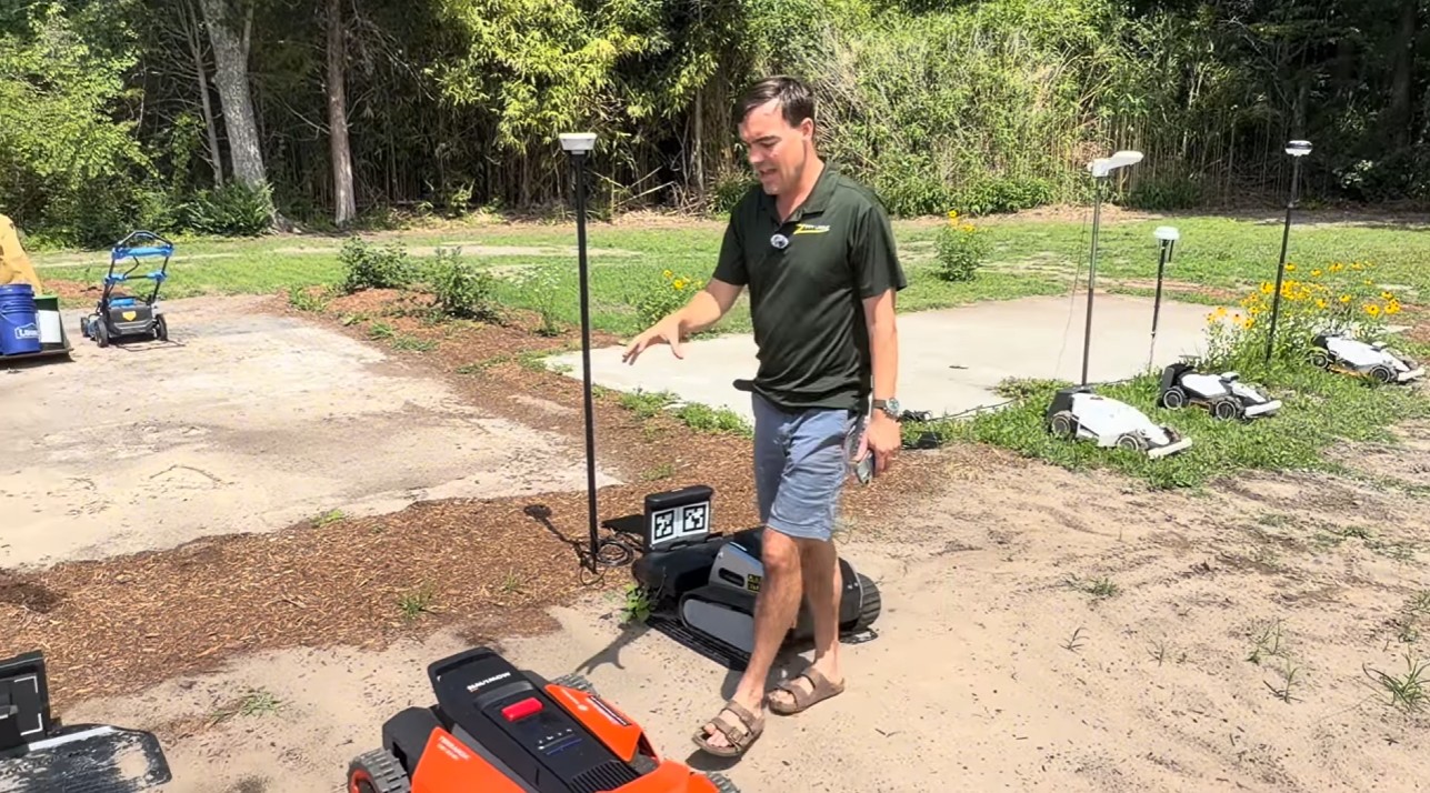 Zippy Lawnz field-testing several large-lawn robot mowers alongside RTK base antennas on tripods