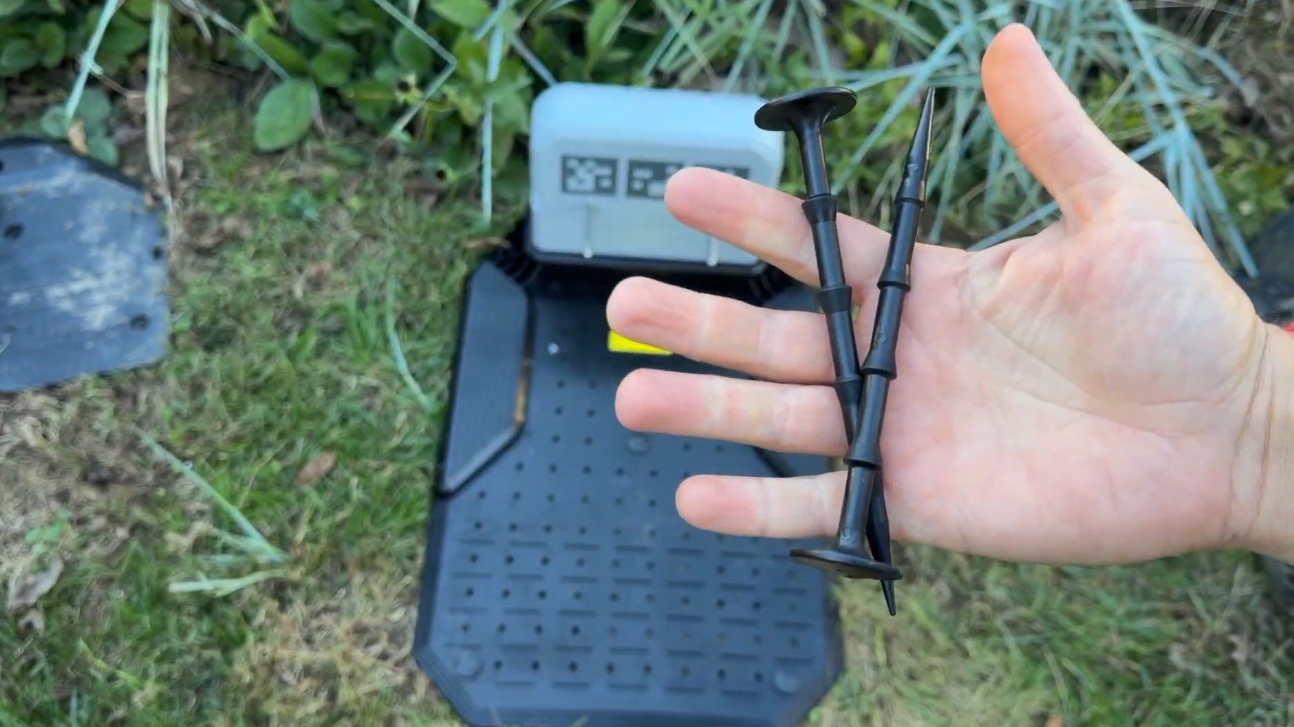 Two plastic stake-down pegs held over the Lopkin L2500 charging station base plate