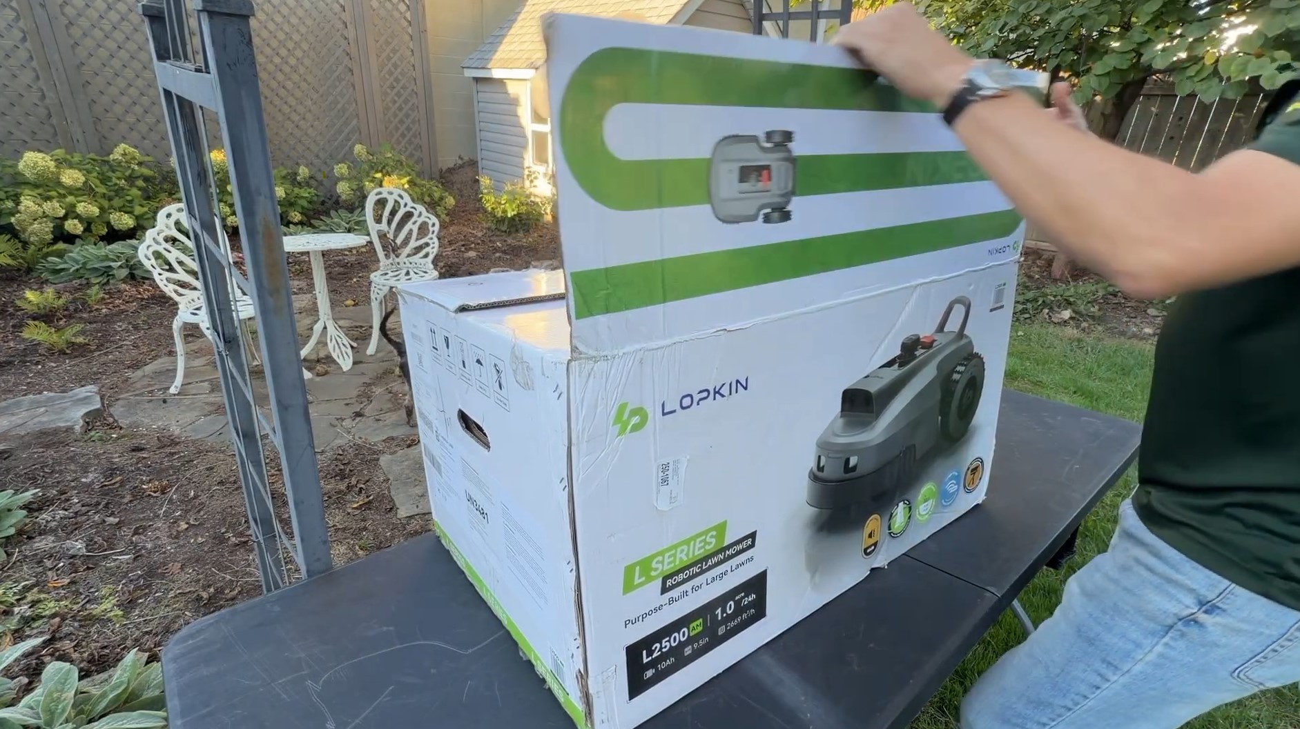 Opening the Lopkin L2500 L Series robotic lawn mower box on a backyard table