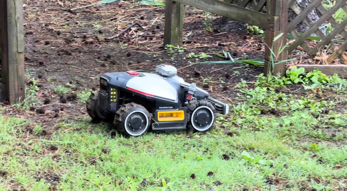 A Mammotion LUBA mowing near heavy tree cover, where LiDAR and camera vision carry the navigation