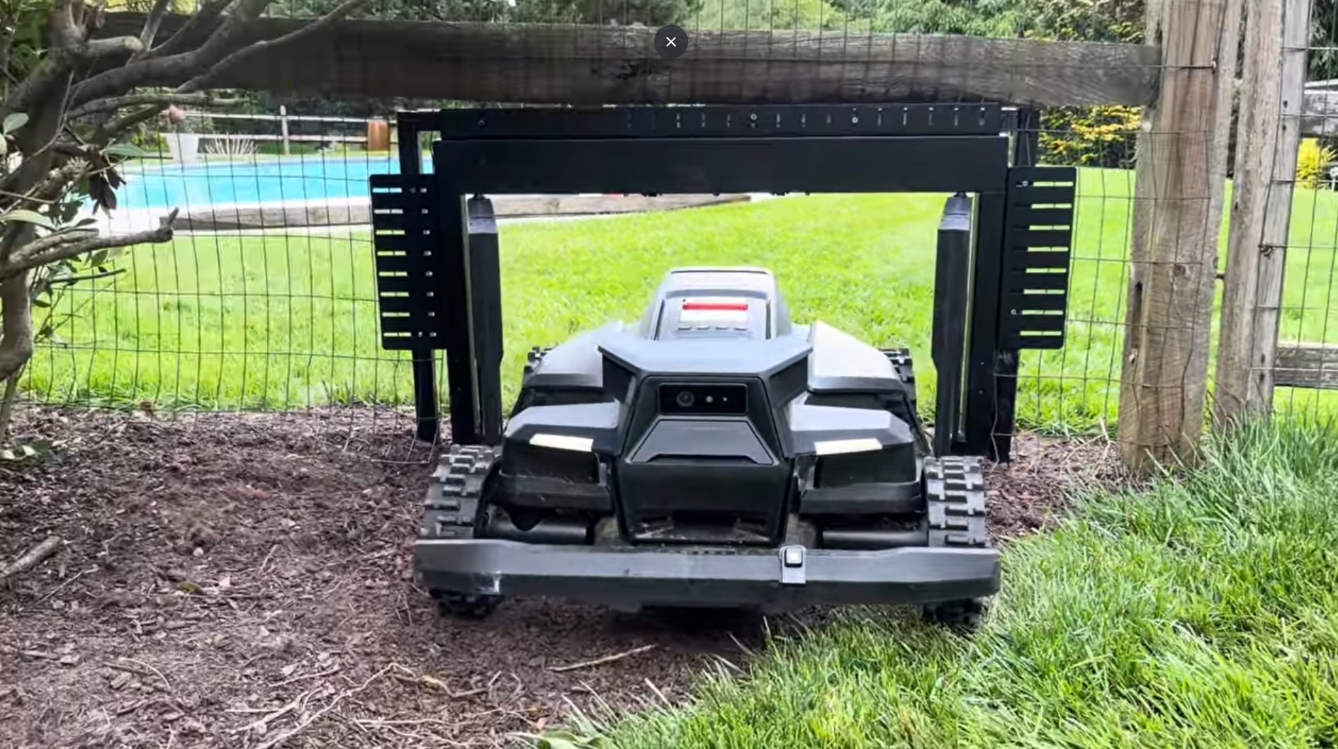 A Navimow mower passing through a MowGate in a welded-wire fence