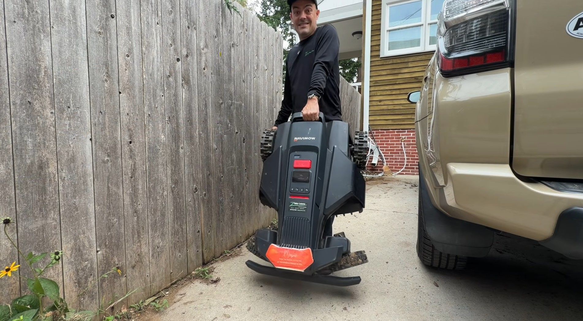 Paul Richards of Zippy Lawnz carrying a Segway Navimow X430 down a driveway during an on-camera anti-theft test