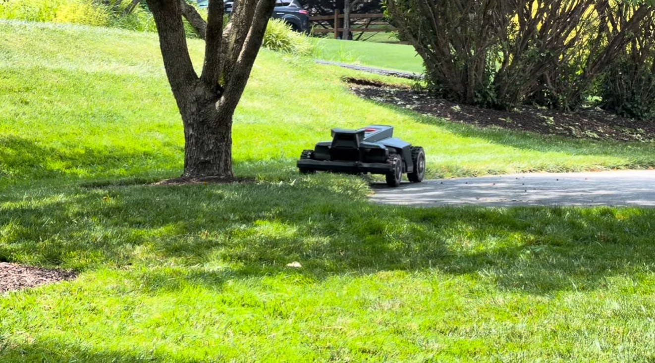 A Navimow X430 robot mower crossing a driveway to mow a separate lawn area
