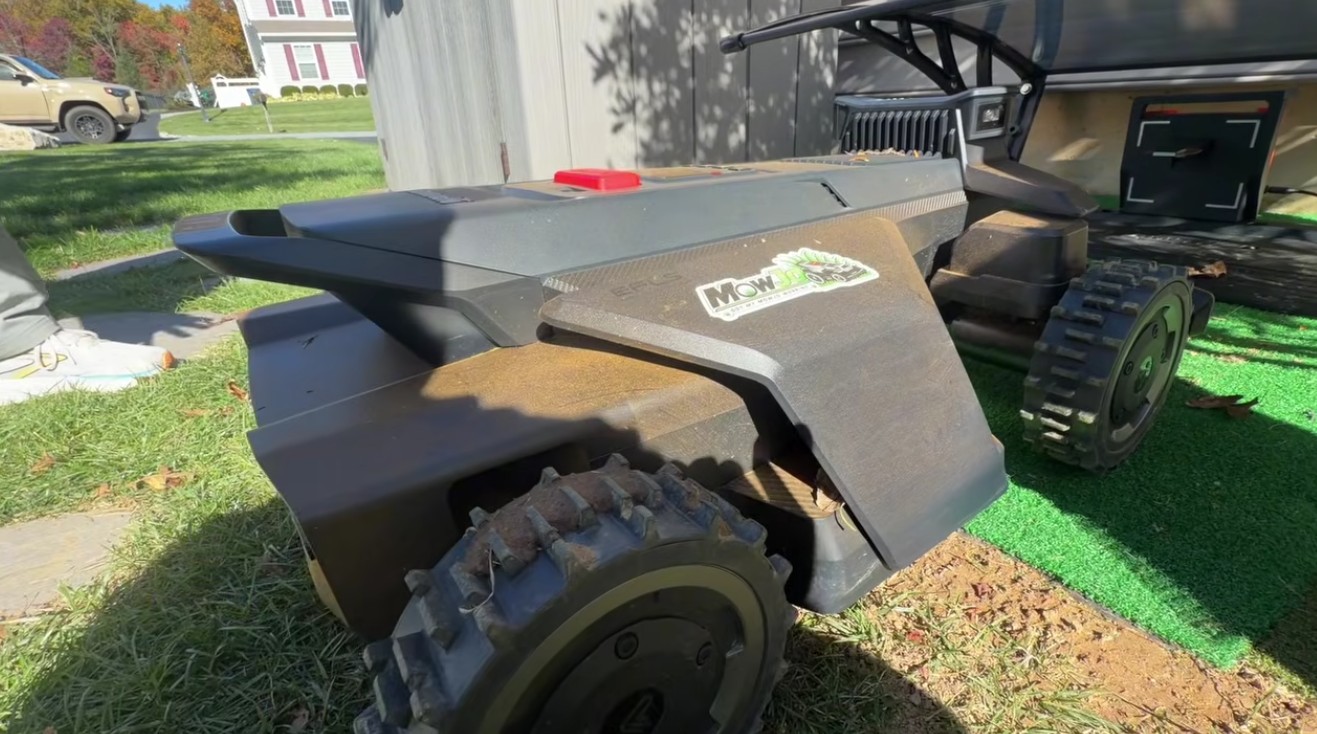 A Segway Navimow X430 named MowJo, with its custom sticker, parked on an artificial turf pad beside its garage at a Downingtown, PA home