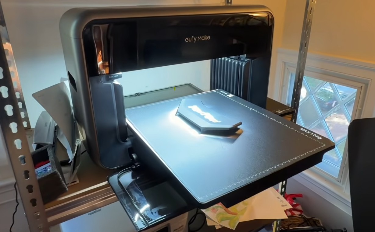 A Navimow decorative camera housing on the bed of the eufyMake UV flatbed printer in the Zippy Lawnz shop