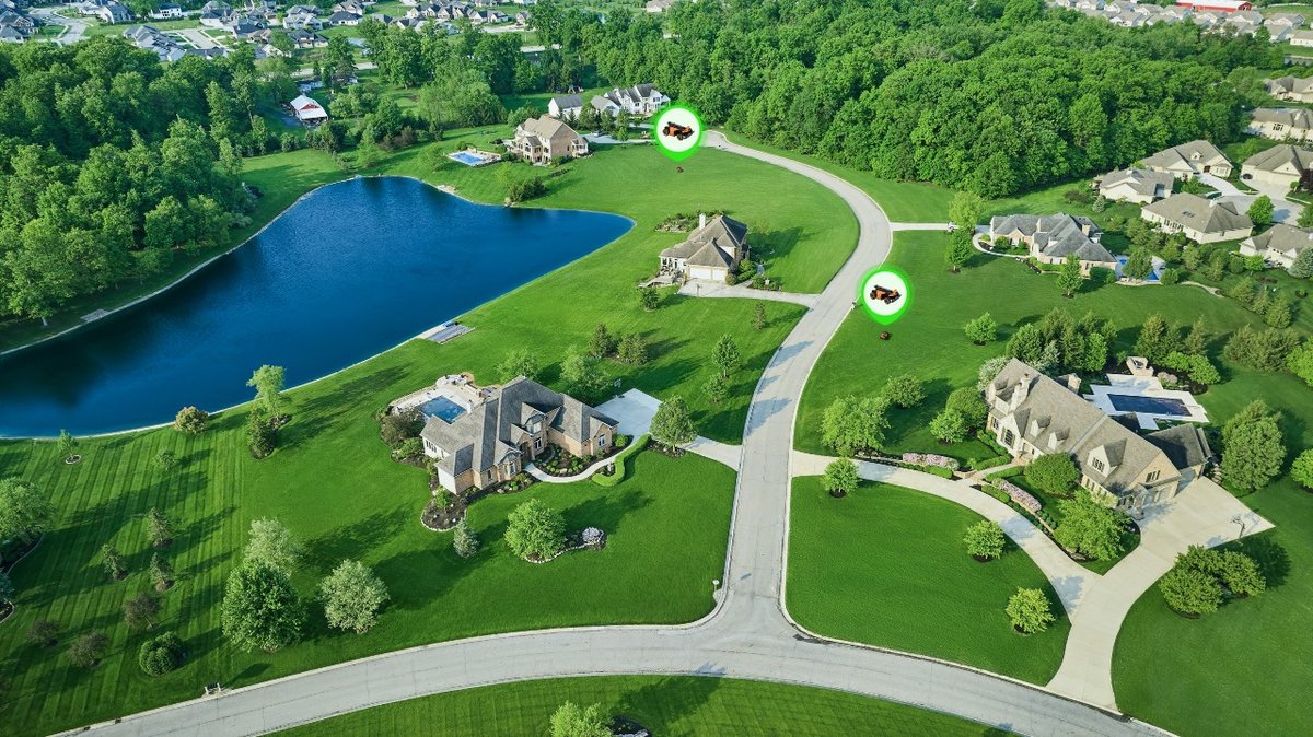 Aerial view of a neighborhood of large lawns, each with a robot mower marked on it