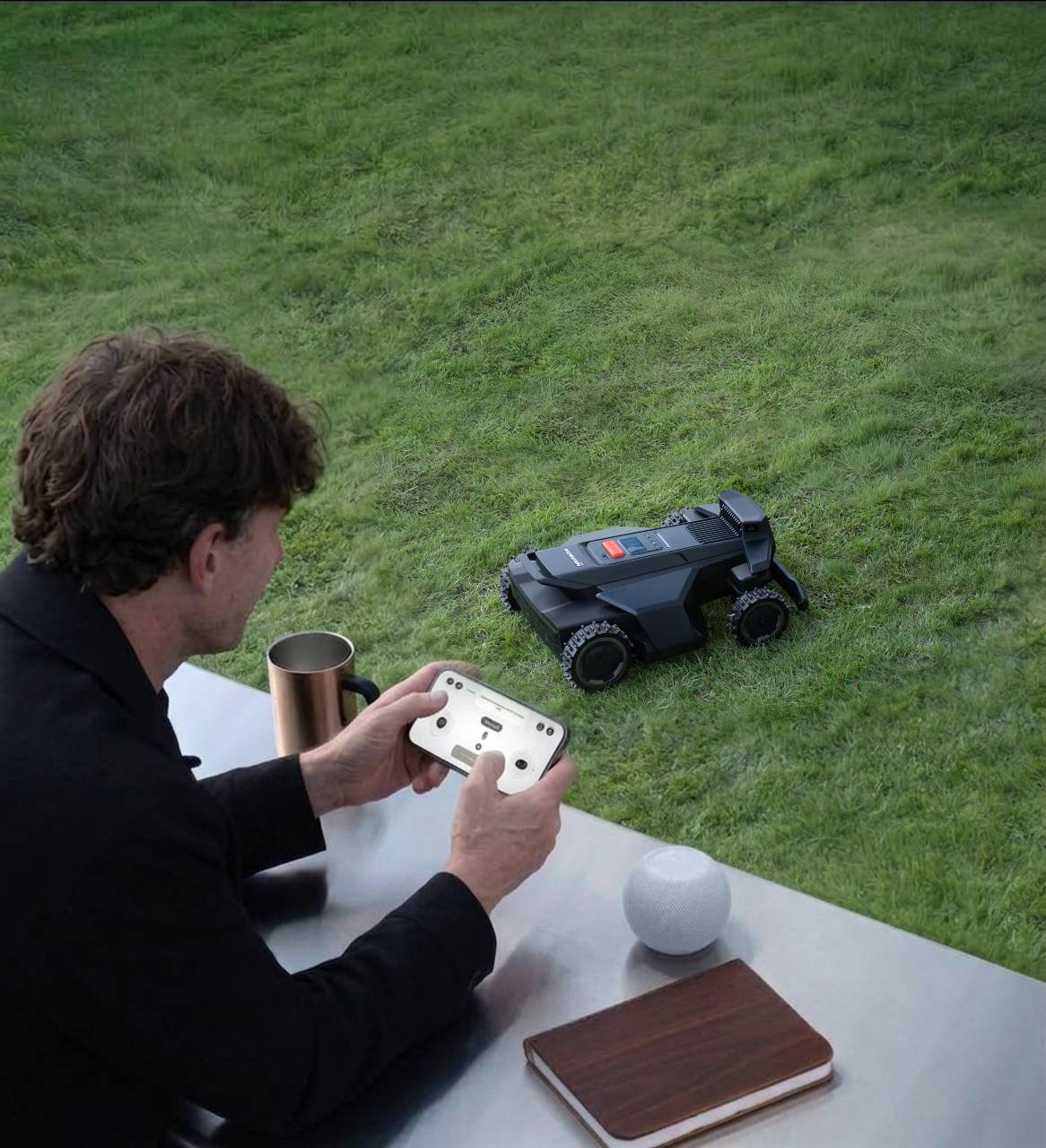 A man with a coffee at a patio table steering a robot mower from his phone
