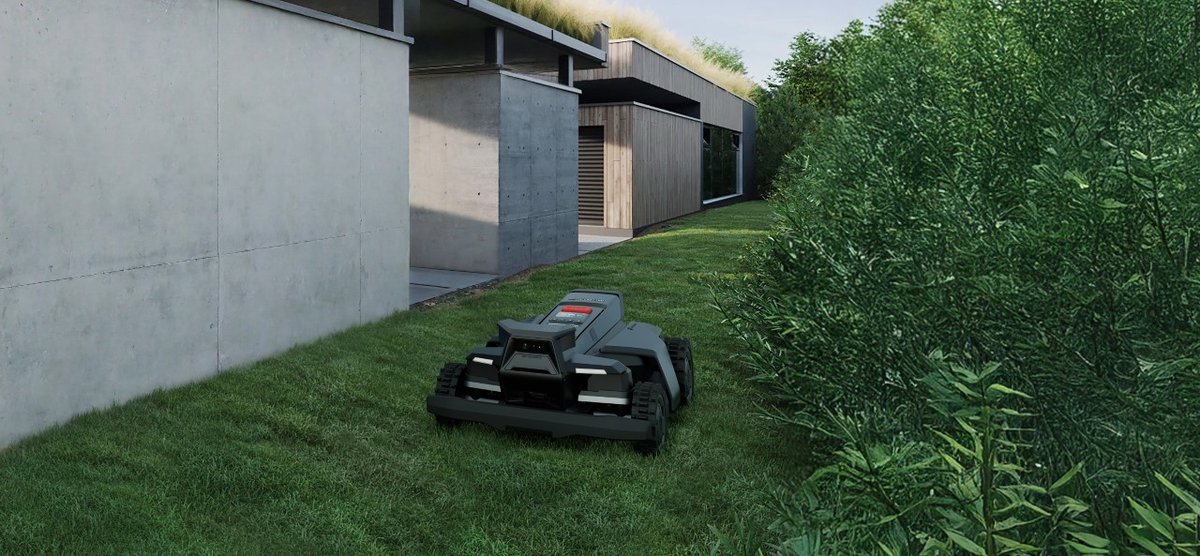 A robot mower cutting a tidy side lawn between a modern home and a hedge